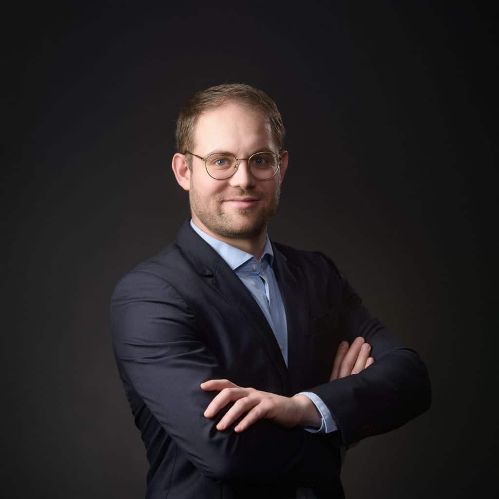 Homme à lunettes en costume, bras croisés, portrait corporate en studio à Annecy