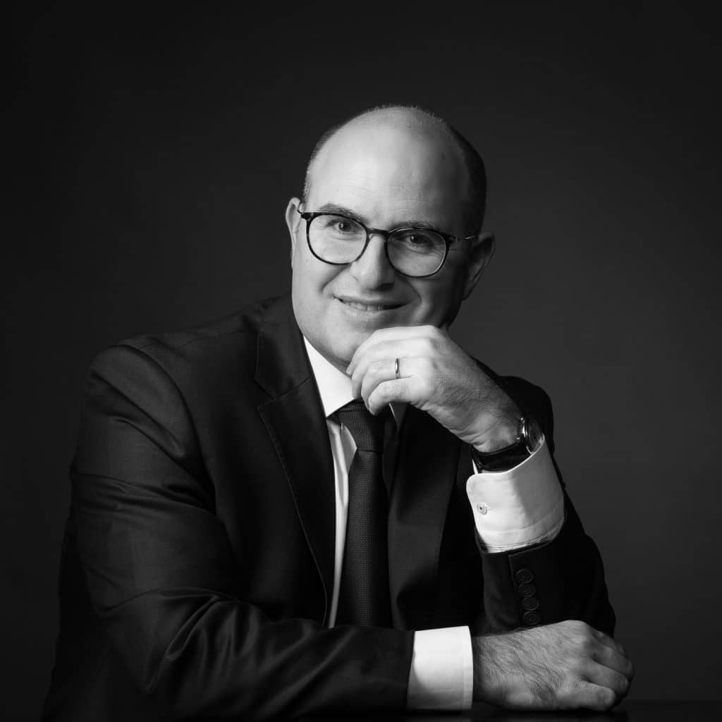 Homme à lunettes en costume, main au menton, portrait corporate en studio à Annecy