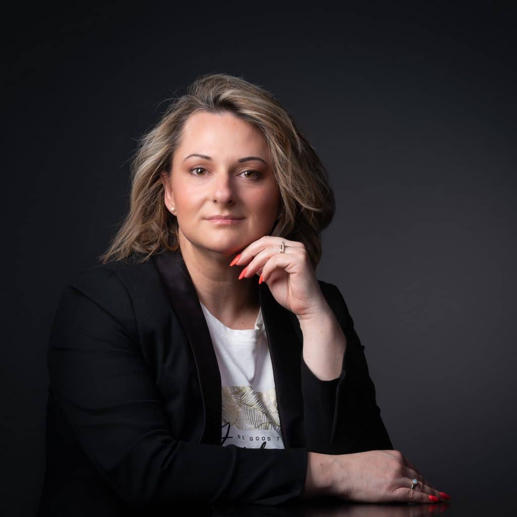 Femme blonde en blazer noir, accoudée, portrait corporate en studio à Annecy