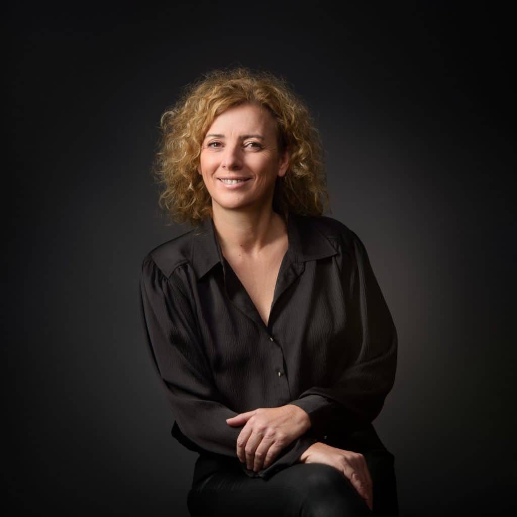 Femme aux cheveux bouclés en chemise noire, portrait corporate en studio à Annecy