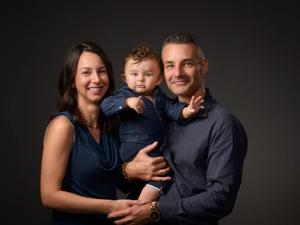 Parents et leur bébé souriants, portrait de famille en studio à Annecy