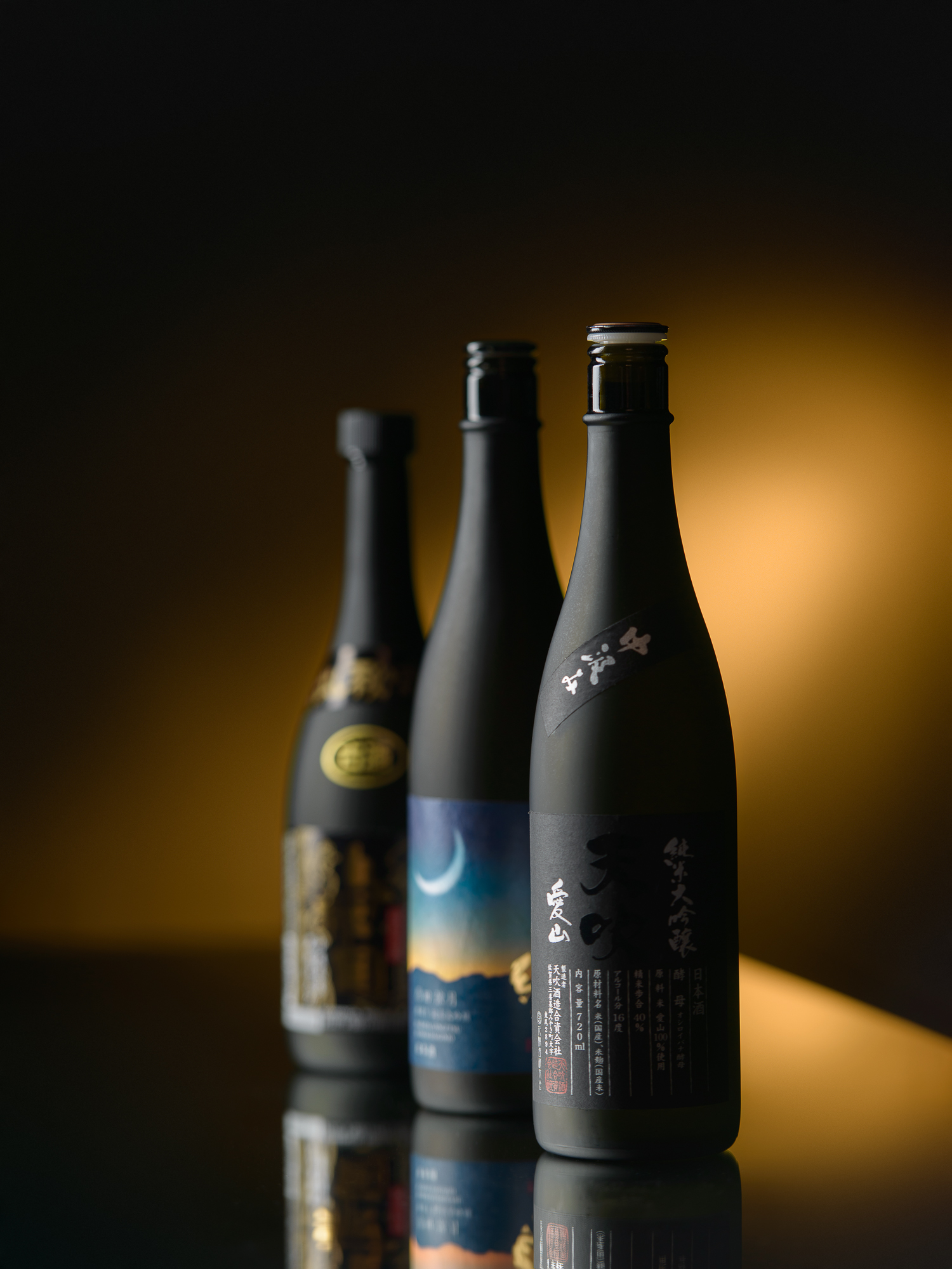 Trois bouteilles sur fond sombre, lumière sculptée, photographie produit