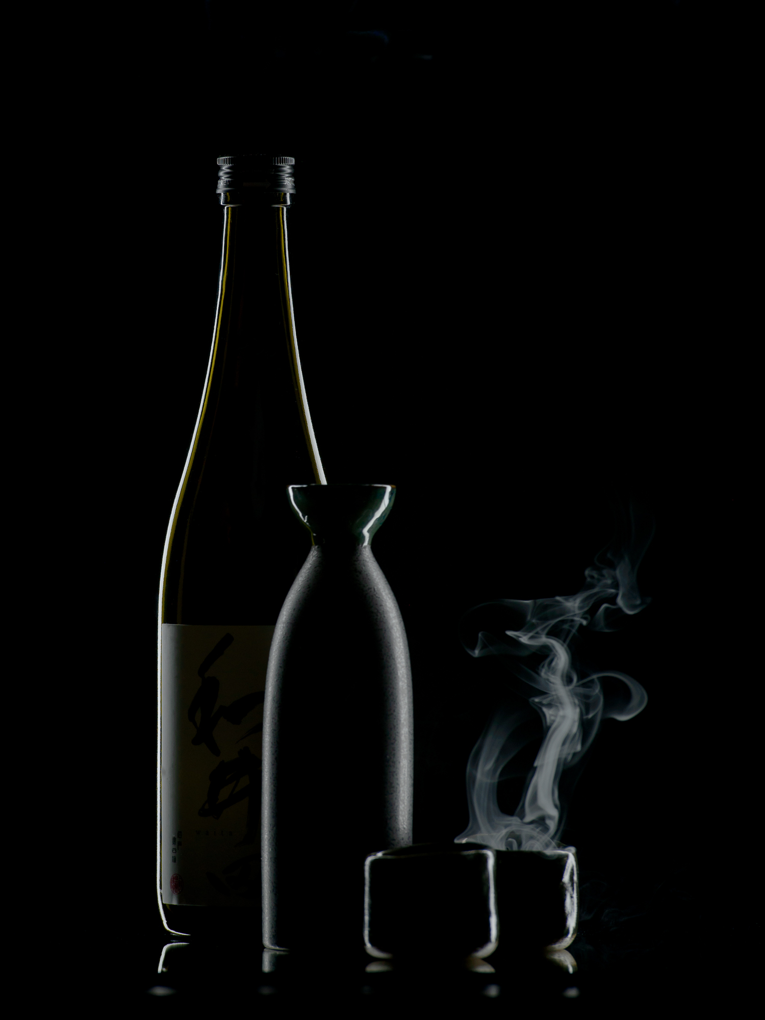 Bouteille et verre en contre-jour sur fond noir