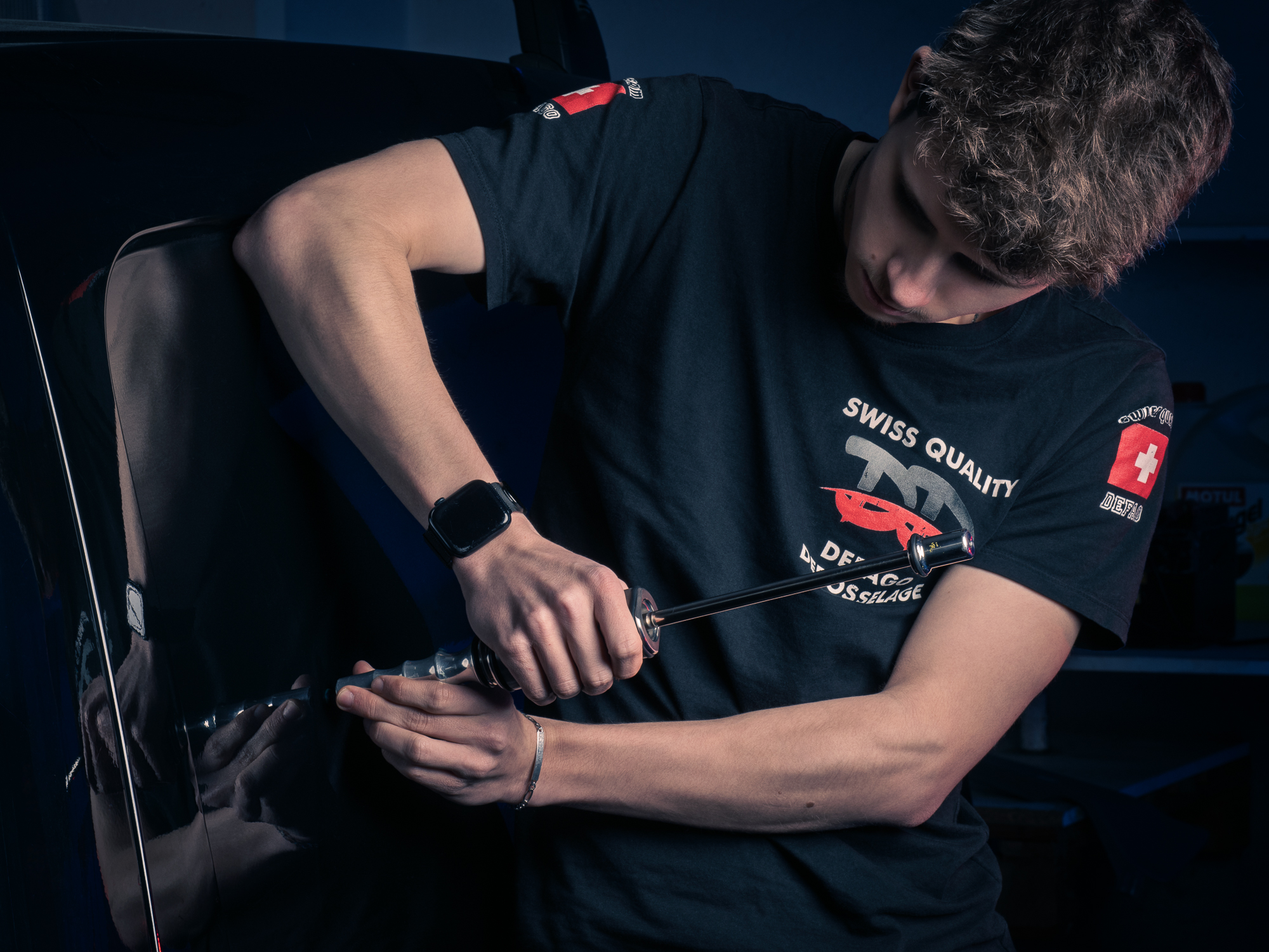 Mains d’un débosseleur au travail sur une voiture