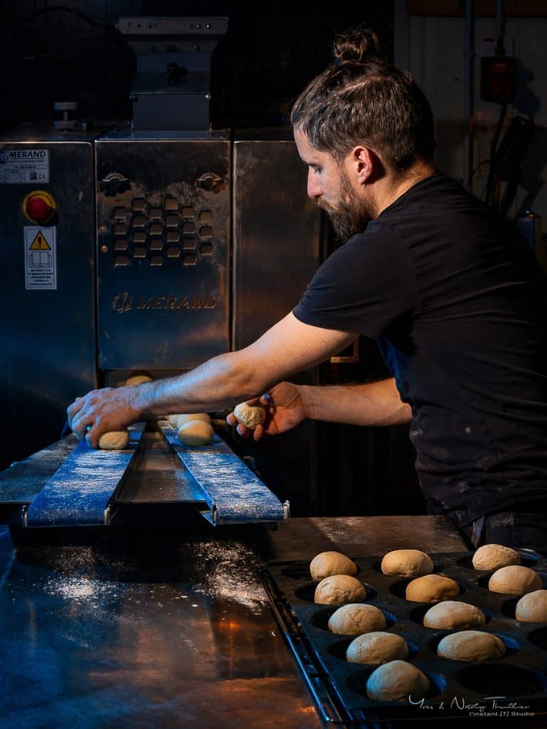 Boulanger au poste de la diviseuse disposant les pâtons en moules, reportage photo d'entreprise