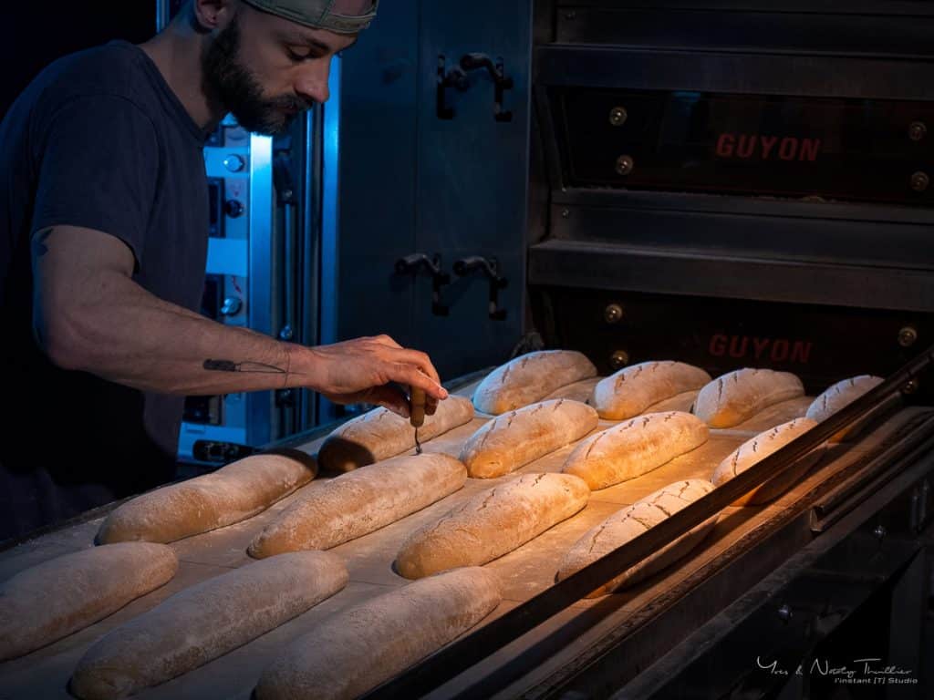 Boulanger grignant les pains devant le four, reportage photo d'entreprise en Haute-Savoie