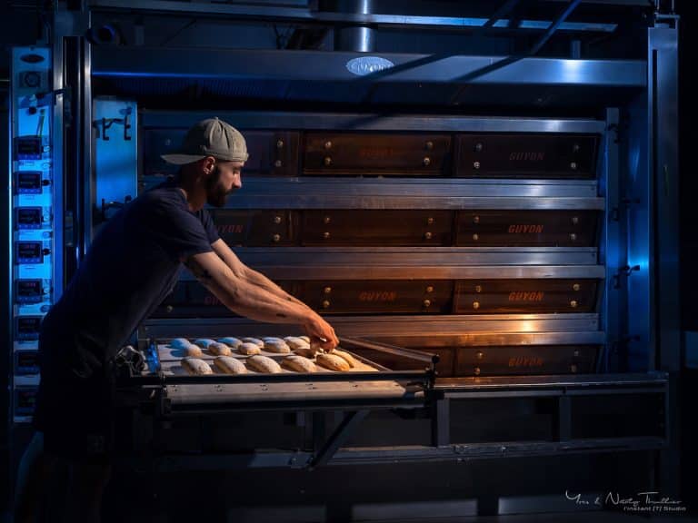 Boulanger enfournant les pains dans un four à soles, reportage photo d'entreprise à Annecy