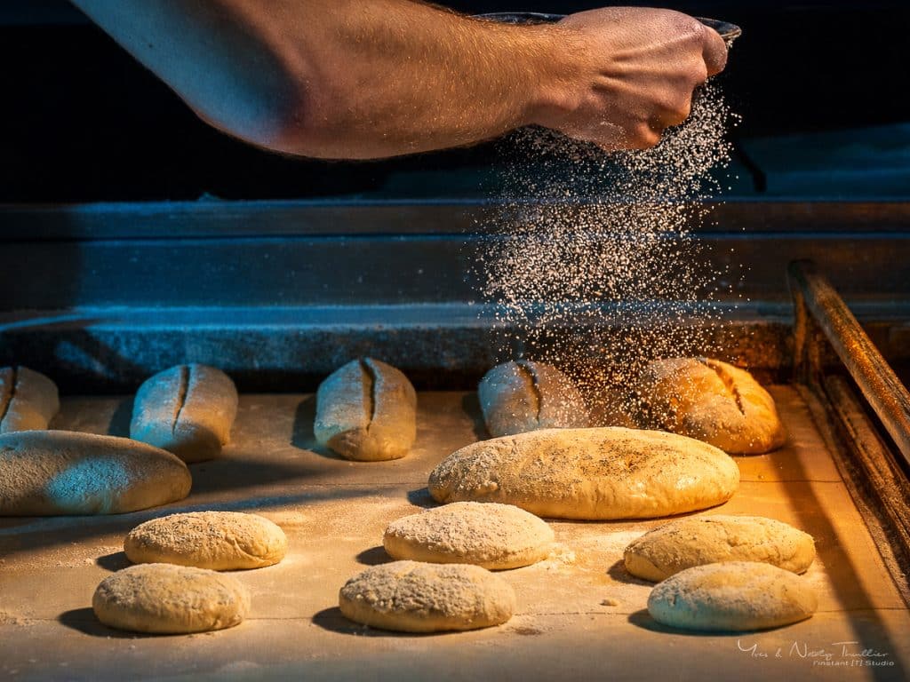 Nuage de farine tombant sur les pains avant enfournement, photographie de boulangerie