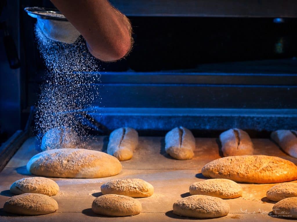 Farine saupoudrée sur les pains avant cuisson, photographie du savoir-faire boulanger