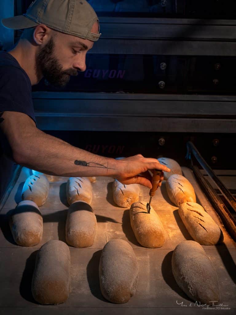 Geste du grignage au couteau sur les pains avant enfournement, reportage photo en boulangerie de production