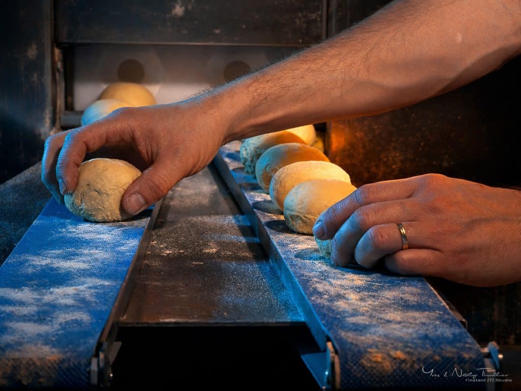 Mains du boulanger disposant les pâtons sur le tapis de la diviseuse